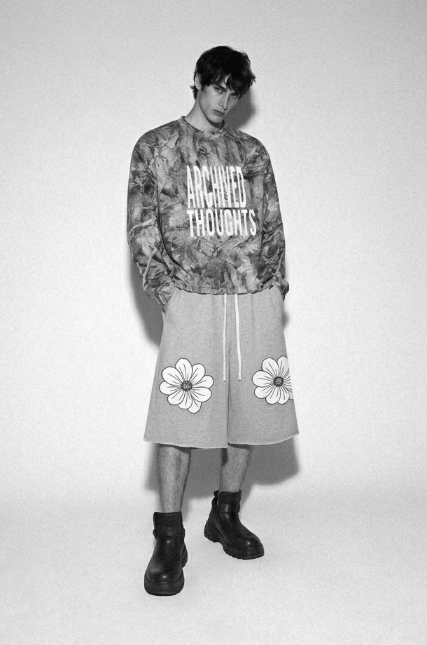 Model wearing the Archived Thoughts camo long-sleeve and flower shorts